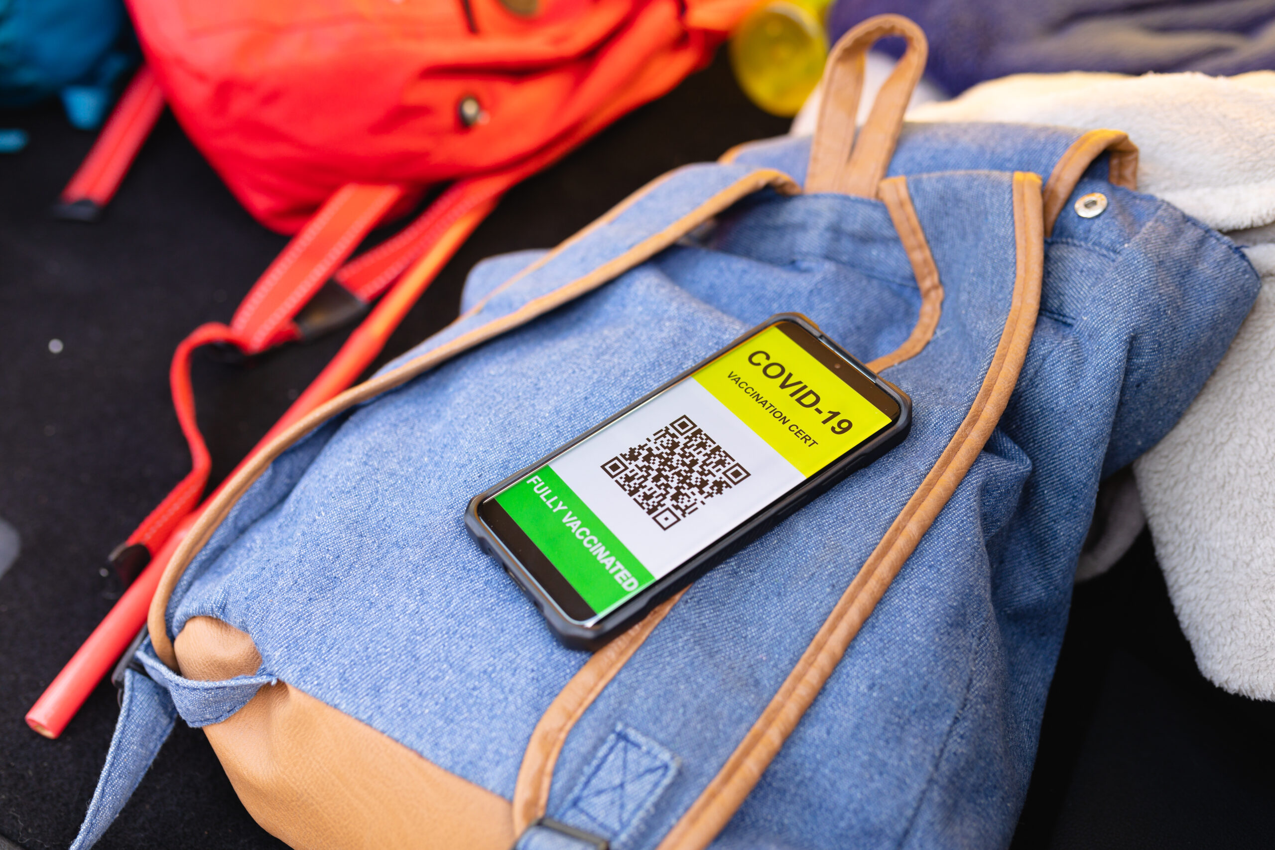 Close-up of covid-19 vaccination certificate on the smartphone on a backpack. covid-19 coronavirus pandemic concept,, unaltered.